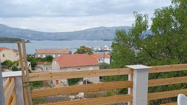 En balkon med udsigt over et sølandskab, både og huse.