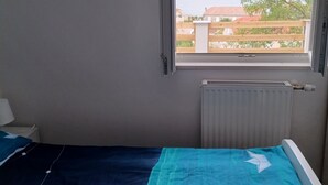 Et soveværelse med vindue med udsigt over en sø og bygninger.
