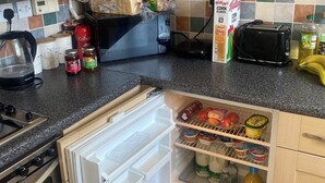A kitchen with a refrigerator, toaster, and various food items on the counter. - Snaith Central Apartment (Goole)