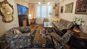 A traditional living room with patterned furniture, a television, a fireplace, and decorative items. - Spacious, stylish and cozy apartment in the very center of Sofia (София)