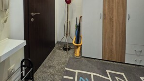 A hallway with a dark wooden door, a white wall-mounted phone, a coat rack with a red bag, and a wardrobe with a wooden panel. - Spacious, stylish and cozy apartment in the very center of Sofia (София)