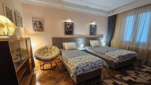 A hotel room with two beds, a round armchair, a wooden cabinet, and a patterned rug. - Spacious, stylish and cozy apartment in the very center of Sofia (София)