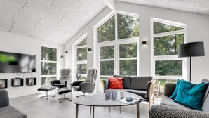 Ein geräumiges Wohnzimmer mit großem Fenster, Flachbildfernseher und modernen Möbeln.