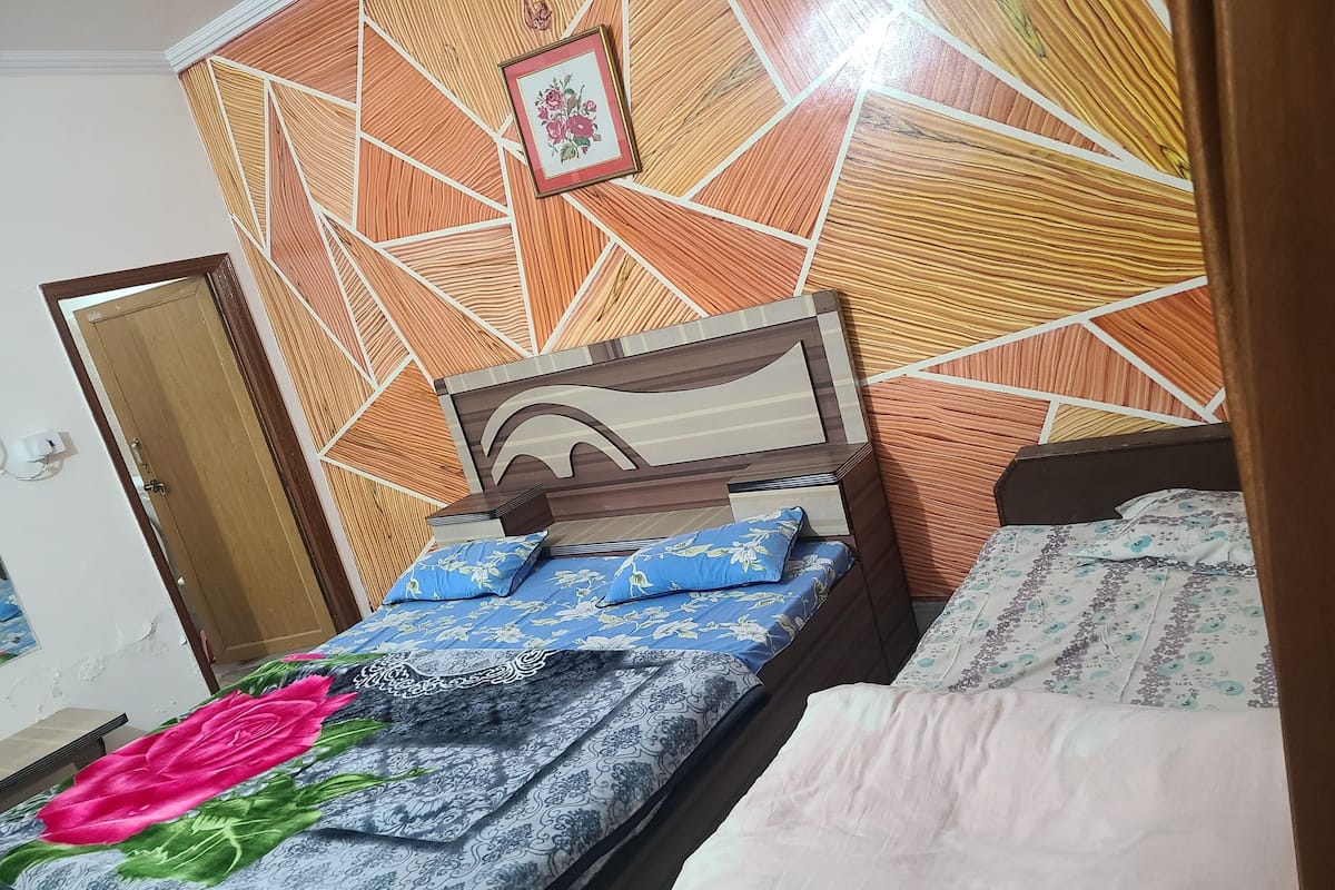 A bedroom with a bed, a bedside table, a wardrobe, and a patterned wall.