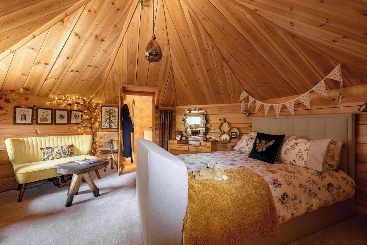 A cozy, wooden interior with a bed, sofa, and a small table.