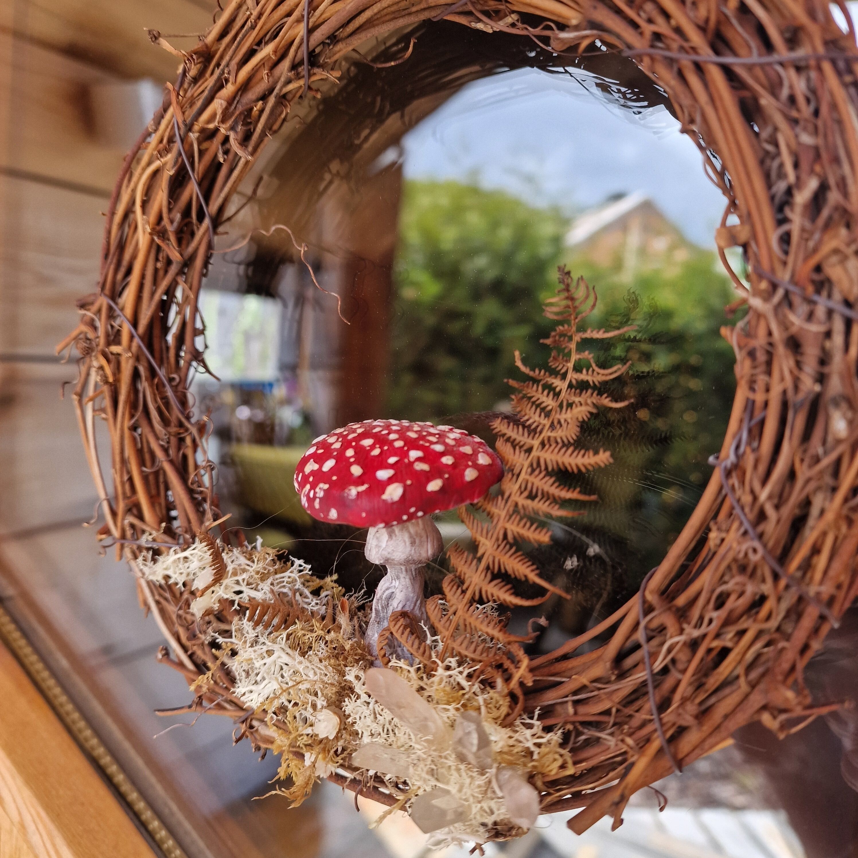 A wreath with a red mushroom and ferns.