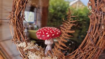 A wreath with a red mushroom and ferns.
