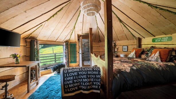 A cozy wooden cabin bedroom with a bed, a desk, and a sign that reads "I LOVE YOUR BEAR HUGS". - Sweet Donside Cabins (Strathdon)