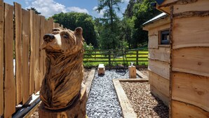 A wooden cabin with a bear sculpture in front. - Sweet Donside Cabins (Strathdon)