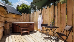 A wooden deck with a hot tub, a table, and a chair. - Sweet Donside Cabins (Strathdon)
