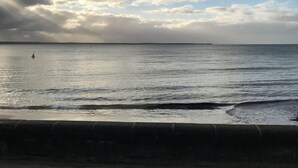 A coastal view with a paved walkway leading to the sea, under a partly cloudy sky. - Perfect location,  5 min walk to the beach, shops. Supermarkets and cafes.  (Cowes)