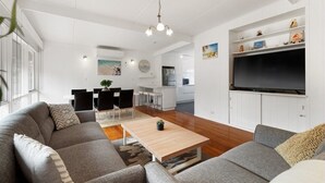 A modern living room with a grey sofa, a wooden coffee table, and a TV mounted on the wall. - Perfect location,  5 min walk to the beach, shops. Supermarkets and cafes.  (Cowes)