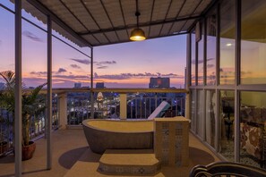 A balcony with a curved seating area, large windows, and a cityscape view at dusk. - ARISON Hotel (Phnom Penh)