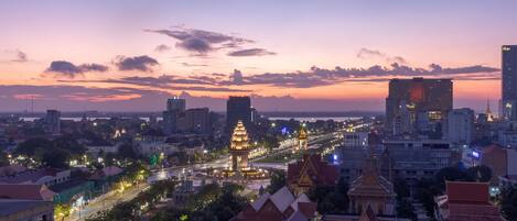 A cityscape at dusk with illuminated buildings, a prominent pagoda, and a mix of traditional and modern architecture.