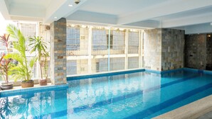 An indoor swimming pool with stone walls and potted plants. - ARISON Hotel (Phnom Penh)
