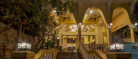 A grand entrance with a staircase, arched ceilings, and a sign for the Arison Hotel.