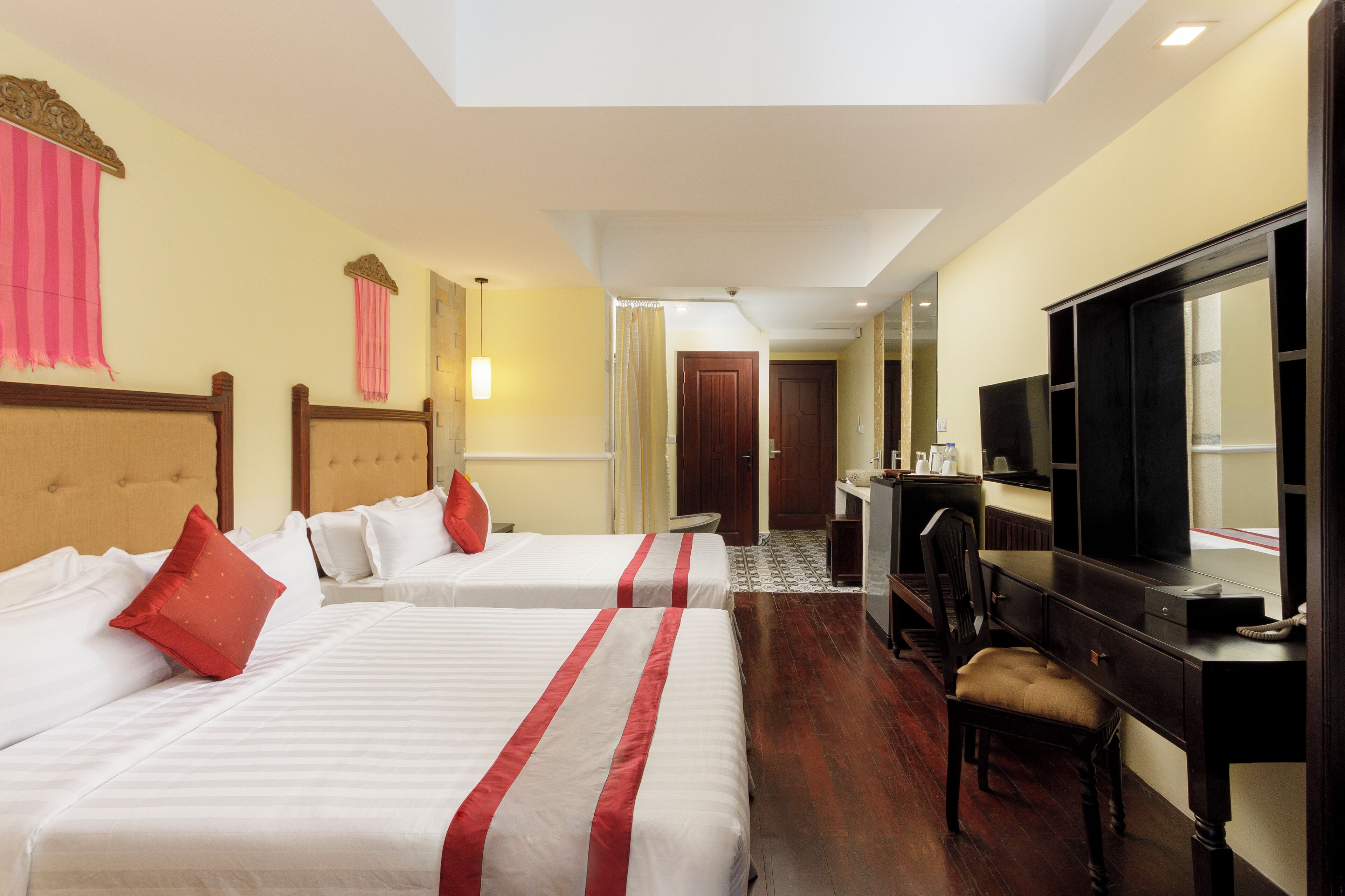 Habitación de hotel con dos camas, un escritorio, una silla, un televisor y un espejo.
