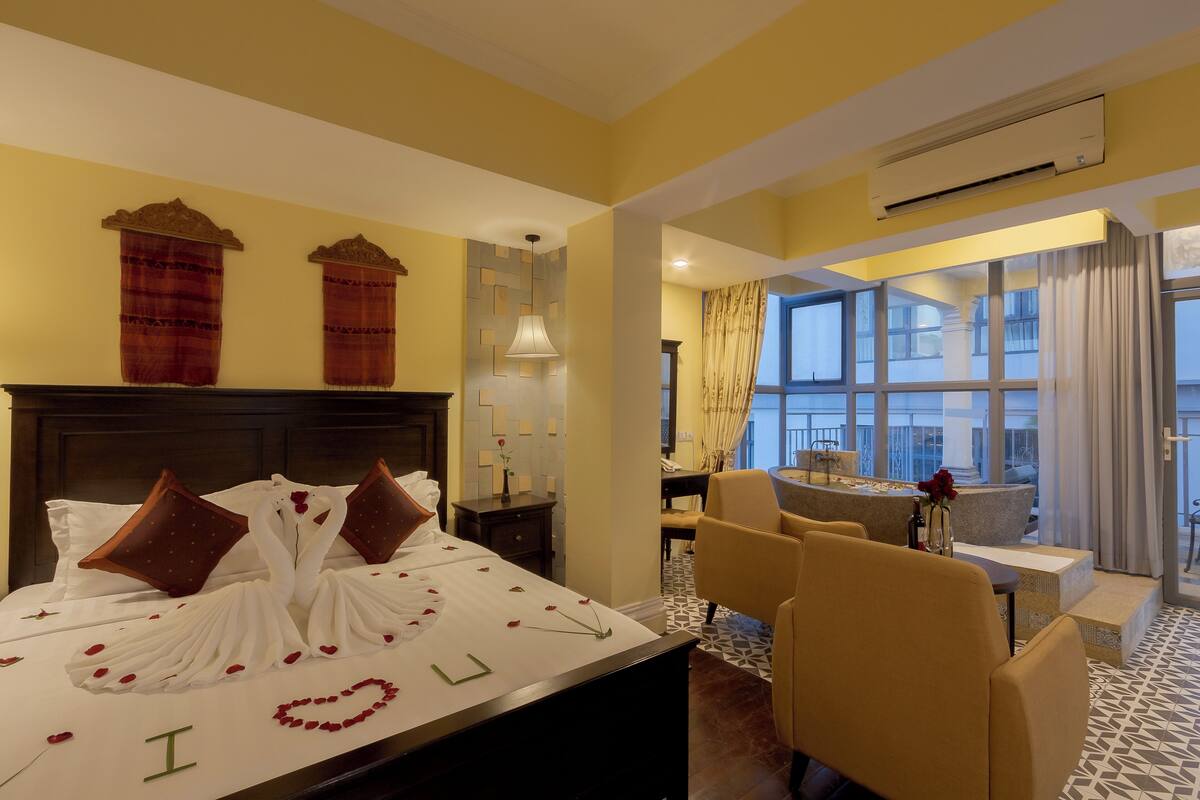 A hotel room with a bed, a desk, a chair, and a view of the outside.