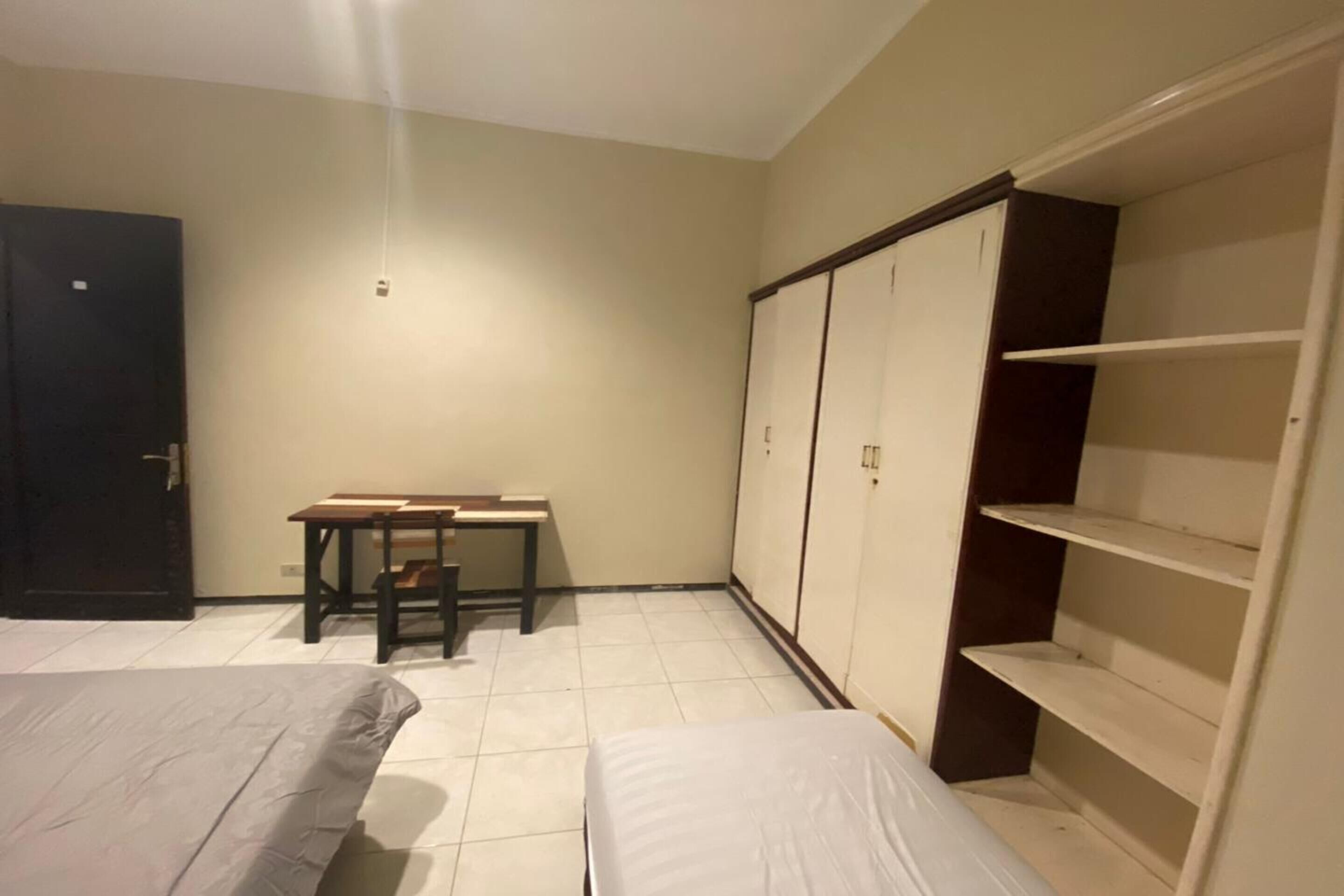 Une chambre avec deux lits, un bureau et une armoire.