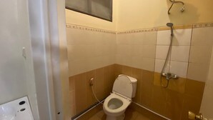 A bathroom with a toilet, a shower, and a window above the toilet. - Hotel O Sweet Home Residence Simpang Lima (Semarang)