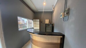 A reception area with a curved reception desk, a window with a view, a wall-mounted intercom, and a small refrigerator. - Hotel O Sweet Home Residence Simpang Lima (Semarang)