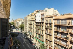 A multi-story building with balconies, a street in front, and a clear blue sky.
