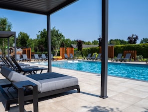 A poolside area with lounge chairs and a covered seating area. - Chalet by Pond With Sauna (Veldhoven)