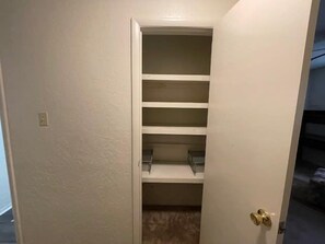 A closed closet with multiple shelves and a door with a brass handle.
