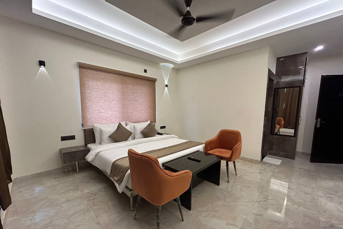 Une chambre moderne comprenant un lit, deux chaises, une table de chevet, un ventilateur de plafond et une porte.