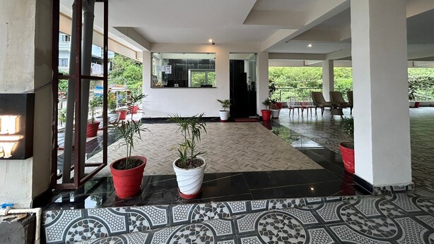 A spacious lobby with a patterned floor, potted plants, and a view of greenery outside. - Hotel Creek Valley Mussoorie (Dehradun)