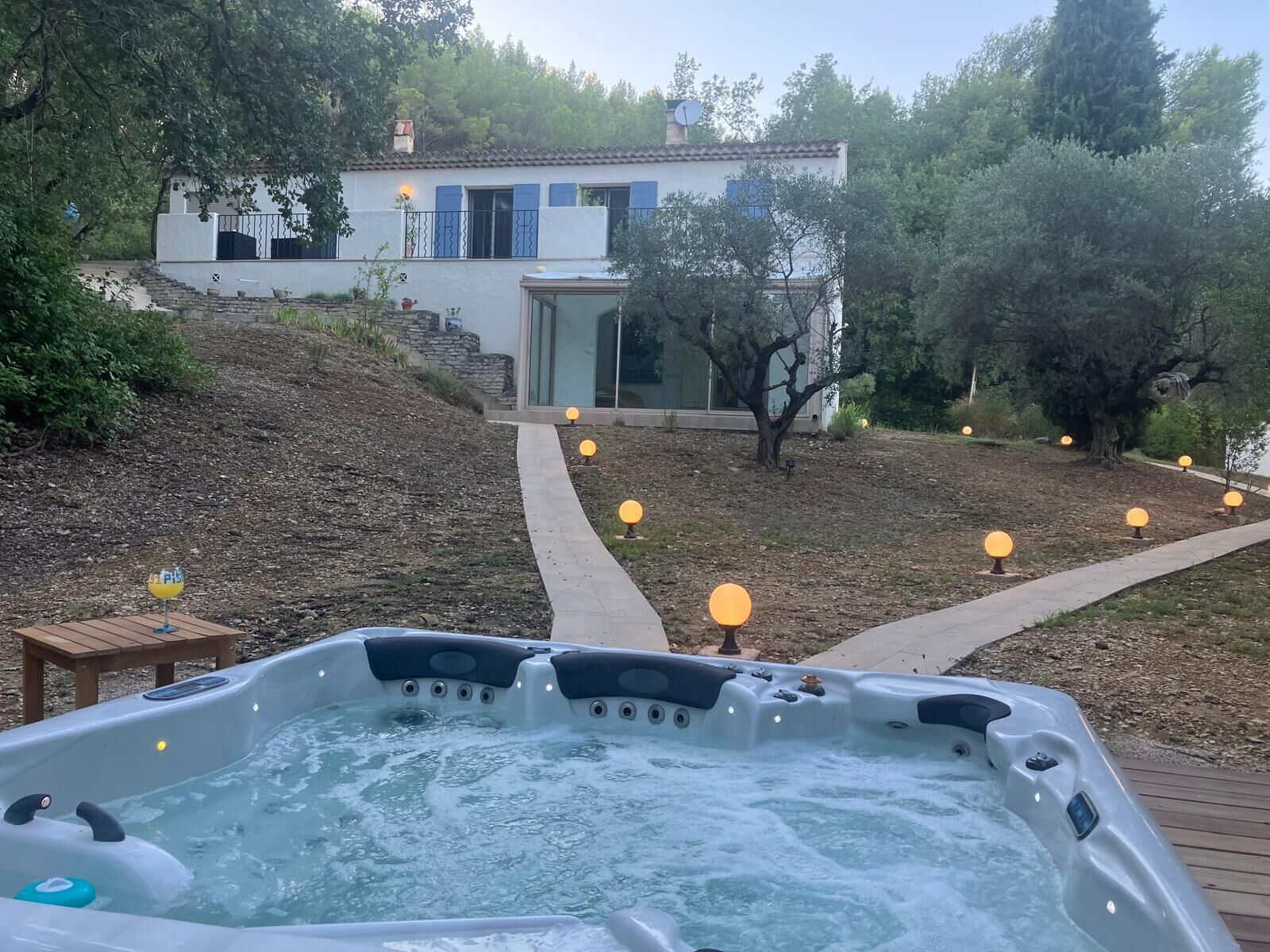 Un bain à remous dans un jardin aménagé, avec une maison en arrière-plan.