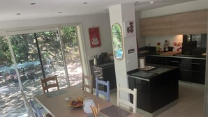 Una cocina moderna con armarios negros, una isla central y una zona de comedor con mesa y sillas.