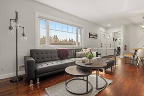 A modern living room with a dark grey sofa, a round coffee table, and a floor lamp.