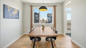 En matplats med ett träbord, svarta stolar, en hängande lampa och en världskarta på väggen.