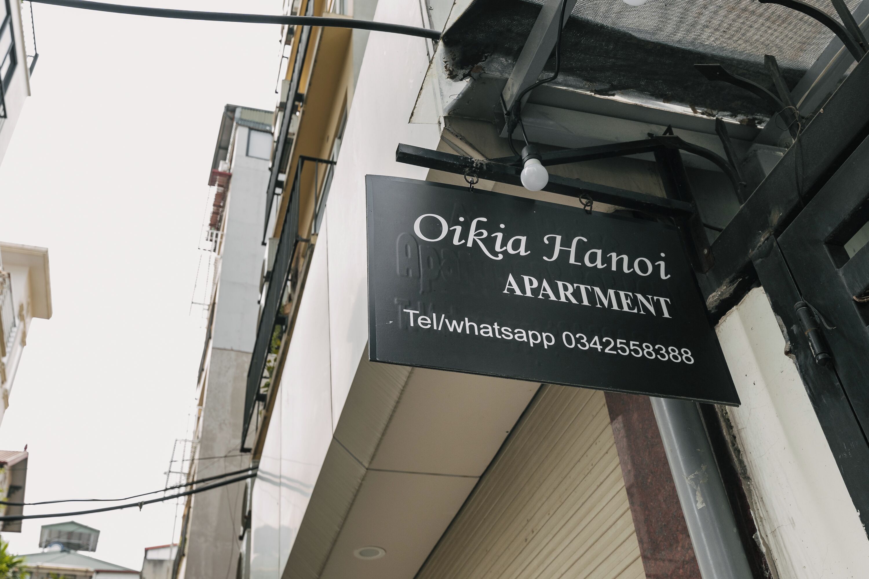 Une enseigne indiquant « Oikia Hanoi Apartment » avec les coordonnées.