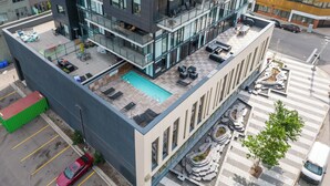 Un bâtiment moderne doté de nombreux balcons, d’une piscine sur le toit et d’une terrasse aménagée.