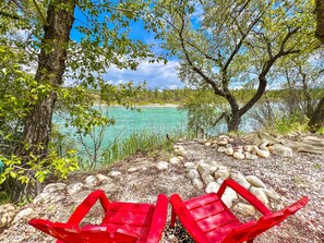 A serene lakeside view with a clear sky, surrounded by trees and a gravel path.