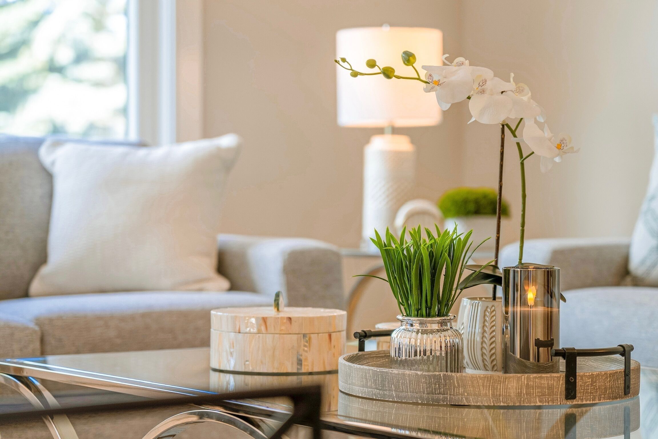 A modern living room with a sofa, a coffee table with decorative items, and a lamp.