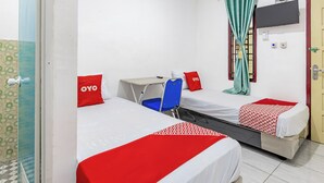 A hotel room with two beds, a desk, and a chair.