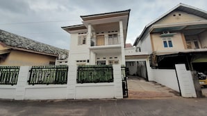 Un edificio residenziale a due piani con un balcone, un garage e un ingresso carrabile recintato.
