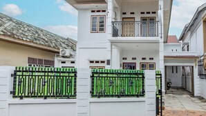 A multi-story residential building with a gated entrance, a balcony on the upper floor, and a visible air conditioning unit.