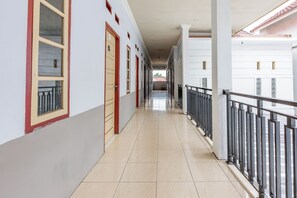A corridor with doors, a balcony with a metal railing, and a tiled floor. - Hotel O Rafie Exclusive 2 Syariah (Jambi)