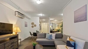 A modern living room with a sofa, TV, and a dining area. - A Modern Studio for 6 Next to Darling Harbour (Sydney)
