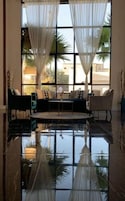 A modern living room with a sofa set, a coffee table, and sheer curtains.