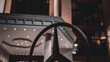 A large, modern building with a prominent Mercedes-Benz logo in the foreground.