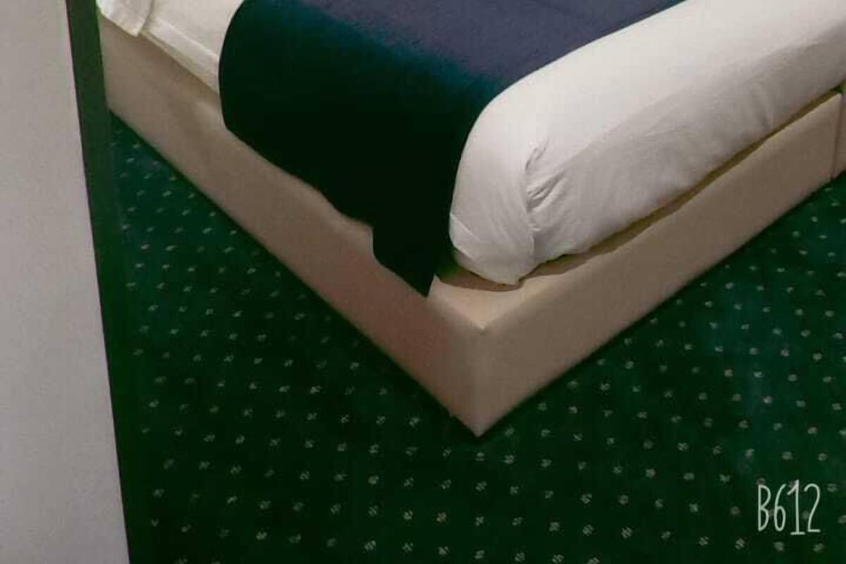 Een hotelkamer met een groot bed, een hoofdbord, een nachtkastje en een lamp.