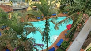 A swimming pool surrounded by palm trees and lounge chairs. - Woodmere Grand Hotel (Nairobi)