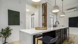 Una cocina moderna con una isla central, iluminación colgante y una pared decorativa de ladrillo.