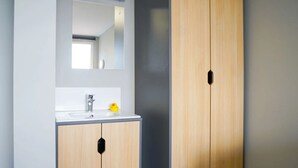 Ein Badezimmer mit einem Holzkosmetikschrank, einem Spiegel und einem gelben Gummientchen.