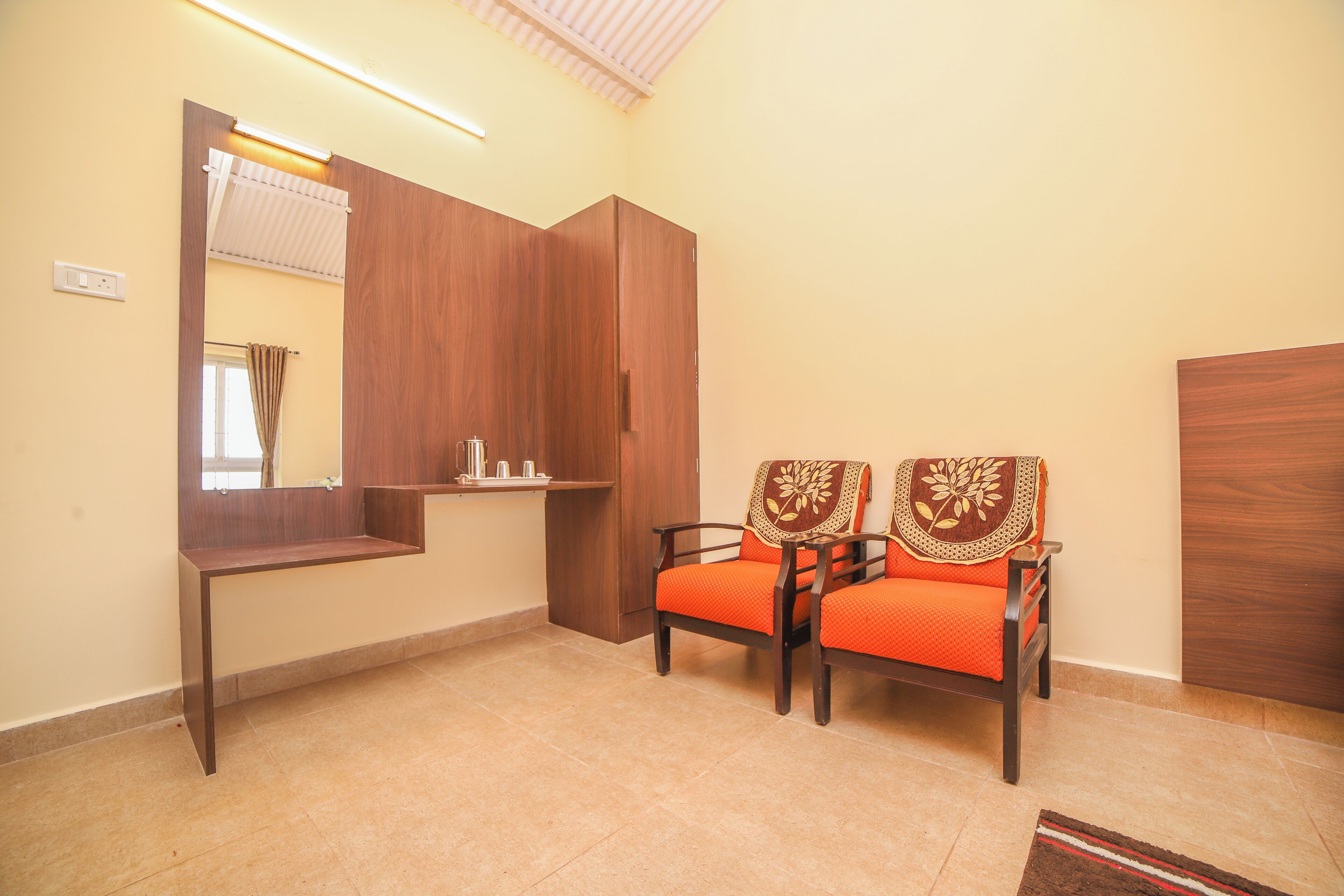 A room with a wooden wardrobe, a bench with orange cushions, and a mirror.